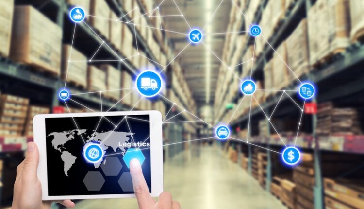 Laptop with white blank screen with global map on brown wooden desk and blurred warehouse store background. Use for cargo Import, Export, Logistics background